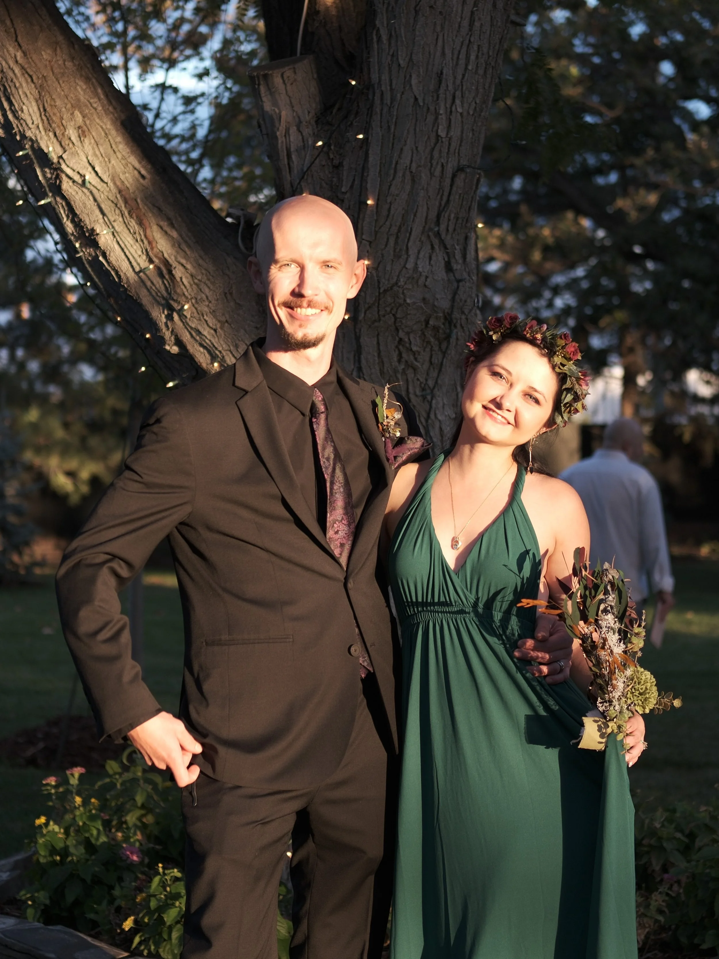 Oskar and Katya smiling together beneath a string-lit tree in golden evening light