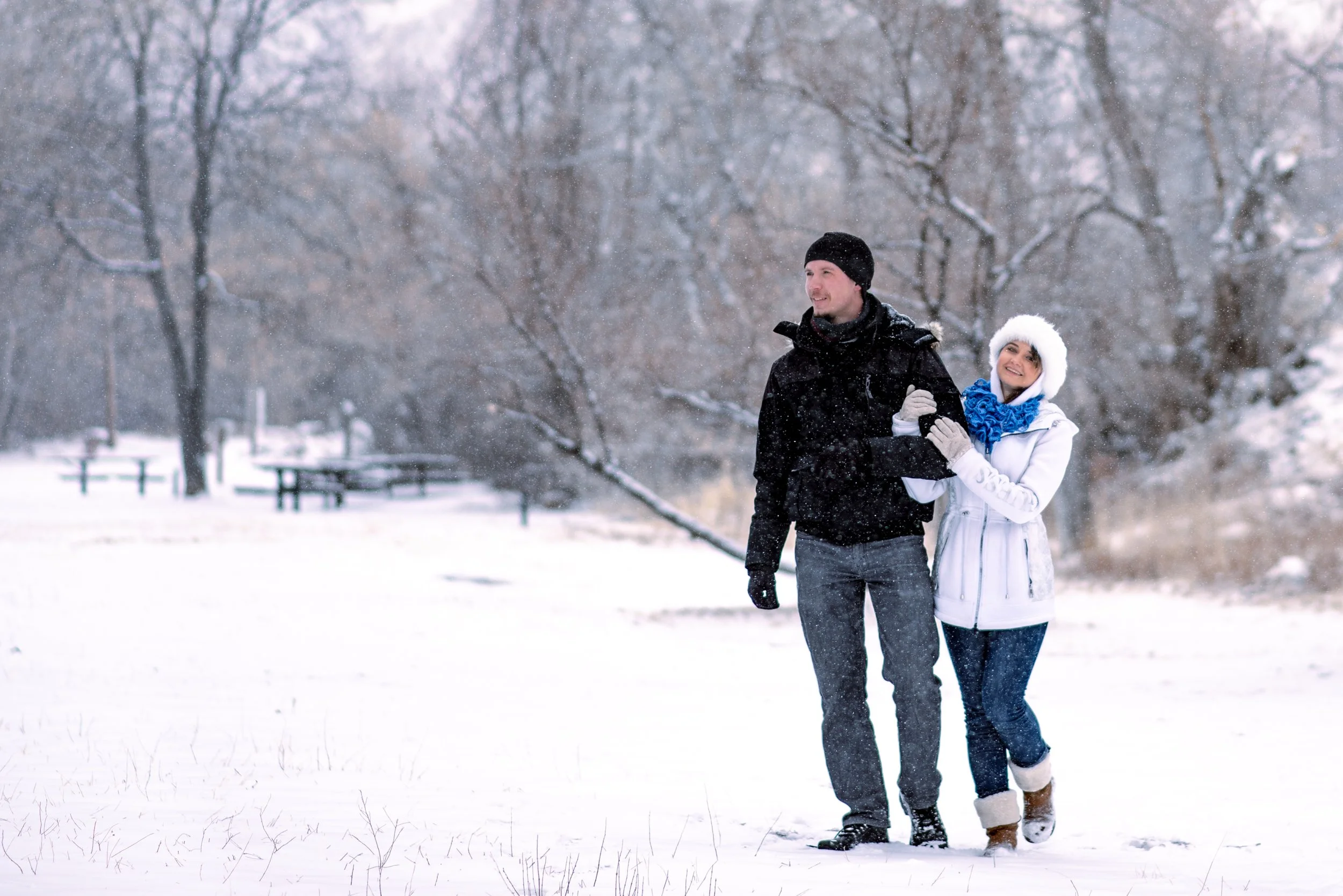 A couple walking arm in arm through falling snow